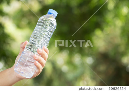young man Hand holding fresh drinking water bottle from a plastic in the park. young man Hand holding fresh drinking water bottle from a plastic in the park. 60626834