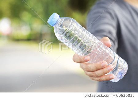young man Hand holding fresh drinking water bottle from a plastic in the park. young man Hand holding fresh drinking water bottle from a plastic in the park. 60626835
