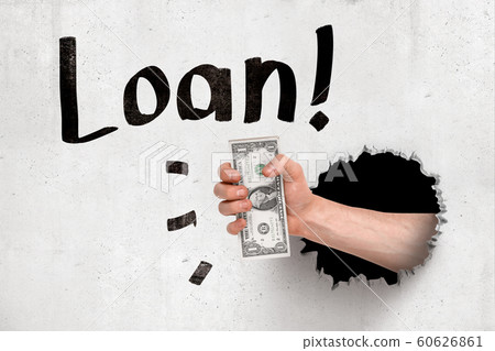 Male hand holding money dollars breaking white wall with black 'Loan' sign on white background Male hand holding money dollars breaking white wall with black 'Loan' sign on white background 60626861