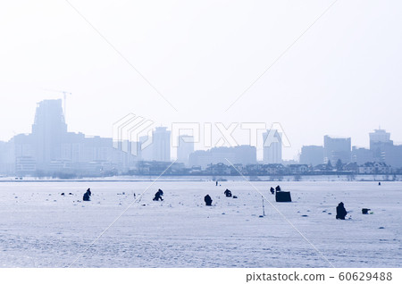 Men fishing on ice in winter. 60629488