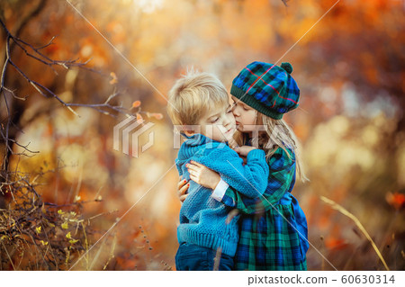 Children dressed in warm autumn clothes hug and smile in the red and yellow forest 60630314