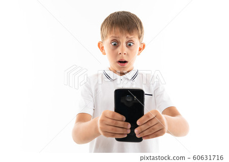 surprised boy looks at the phone on a white background surprised boy looks at the phone on a white background 60631716