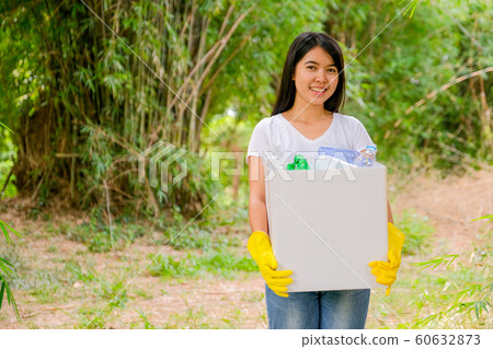 Lovely Asian teen girl with white t-shirt holds box filled with plastic bottles Lovely Asian teen girl with white t-shirt holds box filled with plastic bottles 60632873