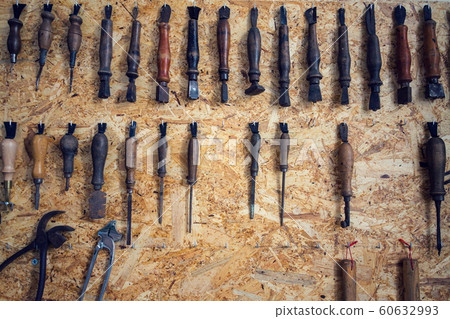 Group of old cobblers tools for handmade shoes production, awls and tongs for leather on wooden chipboard background, flat lay view Group of old cobblers tools for handmade shoes production, awls and tongs for leather on wooden chipboard background, flat lay view 60632993