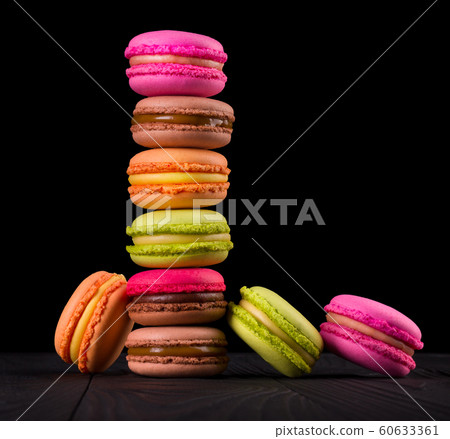 Heap of french colorful macaroons on wooden table isolated on black 60633361