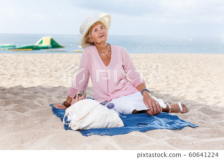 Elderly woman relaxing on beach 60641224