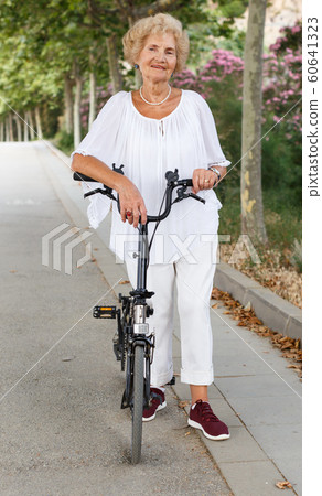 Senior woman resting near bike Senior woman resting near bike 60641323