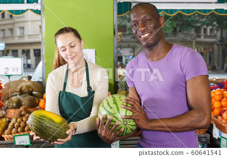 Man client is asking from seller female about freshness watermelon and melon 60641541