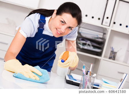 Young and smiling woman in gloves cleaning table Young and smiling woman in gloves cleaning table 60641580