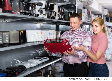 Smiling couple looking for new modern toaster in shop 60641723