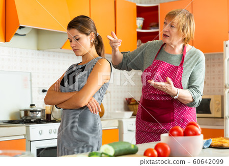 Daughter and mother swearing in kitchen Daughter and mother swearing in kitchen 60642099