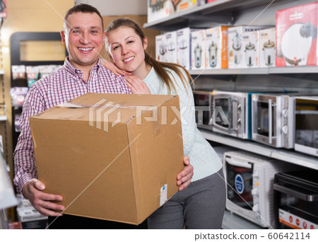 Couple with packed purchases in shop of household appliances 60642114