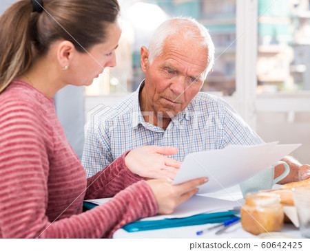 Sad young woman and father with financial documents at home Sad young woman and father with financial documents at home 60642425