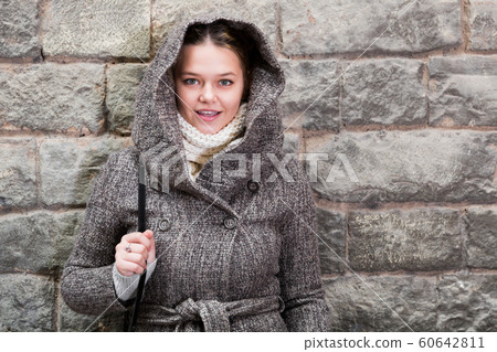cheerful female in coat hood near wall 60642811