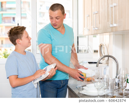 Smiling bou is washing dishes with his father together Smiling bou is washing dishes with his father together 60642874
