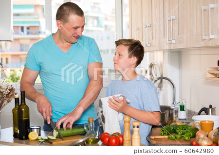 Father and his young son are satisfied of cooking soup together Father and his young son are satisfied of cooking soup together 60642980
