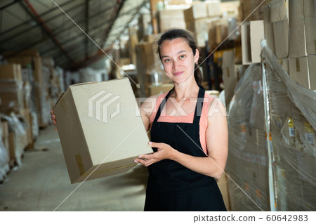 Happy female seller holding box in warehouse Happy female seller holding box in warehouse 60642983