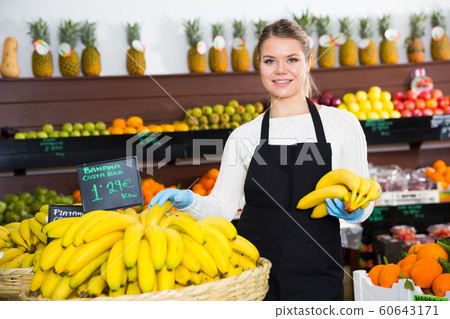 Young female seller in gloves selling fresh bananas on the market Young female seller in gloves selling fresh bananas on the market 60643171