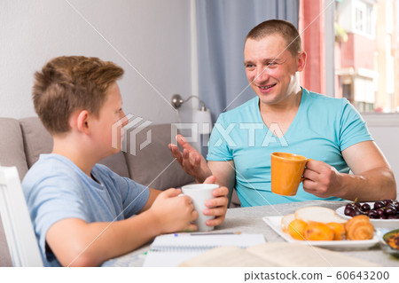Adult male with his son are resting together and talking about teenage secrets Adult male with his son are resting together and talking about teenage secrets 60643200