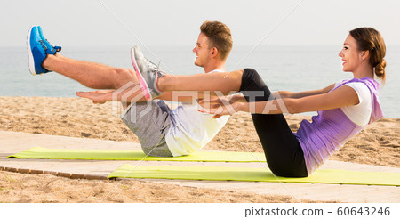 Laughing young couple running on beach by sea Laughing young couple running on beach by sea 60643246