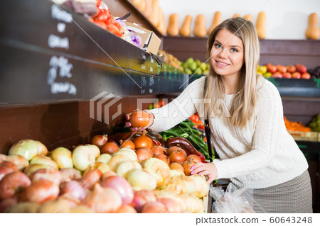 Woman choosing vegetables in greengrocery 60643248