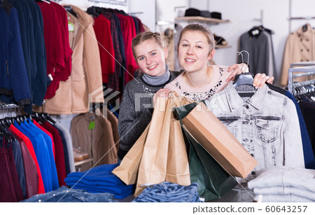 Woman and daughter after shopping in clothing store 60643257