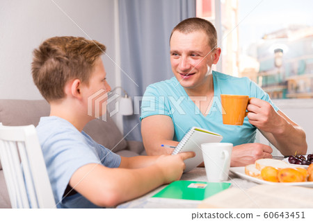 Man with his adult son are reading book together for homework Man with his adult son are reading book together for homework 60643451