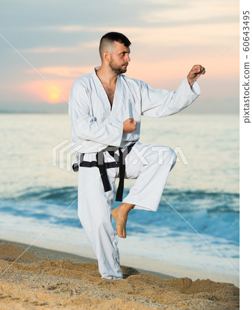 Cheerful male doing karate at ocean quay Cheerful male doing karate at ocean quay 60643495