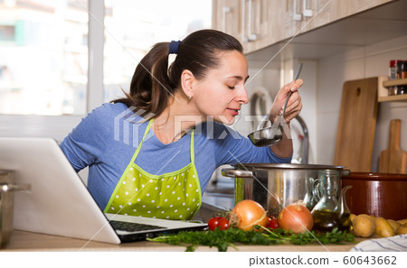 Housewife cooking with help of laptop 60643662