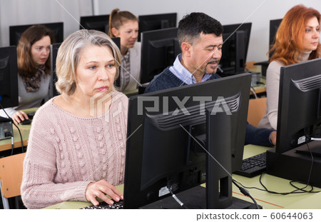 Young and older businesswomen and businessmen in open plan office Young and older businesswomen and businessmen in open plan office 60644063