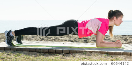 Woman exercising yoga poses on beach Woman exercising yoga poses on beach 60644142