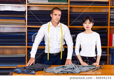 Portrait of confident male tailor with young female assistant st Portrait of confident male tailor with young female assistant st 60644234