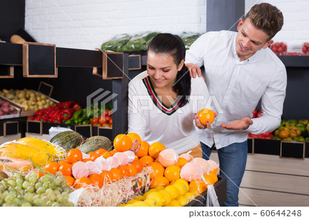 Happy loving couple deciding on fruits in shop Happy loving couple deciding on fruits in shop 60644248