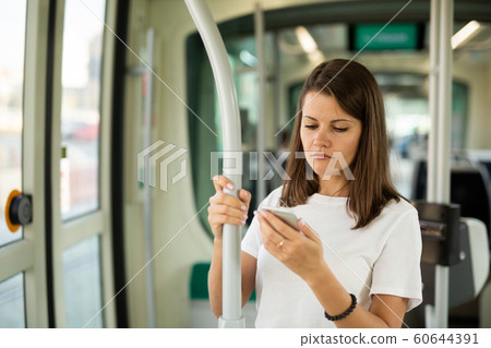 Female using mobile phone in tram 60644391