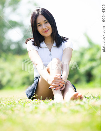 Girl sitting on the green grass in the park Girl sitting on the green grass in the park 60644506