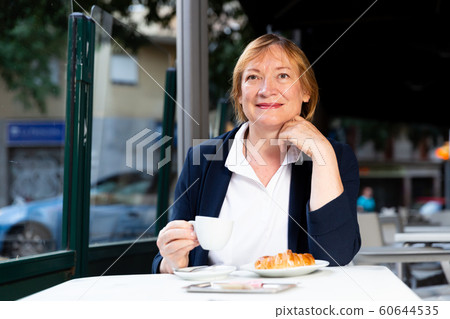 Senior woman having breakfast in cafe 60644535