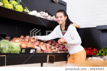 Customer examining various onions in grocery shop Customer examining various onions in grocery shop 60644845