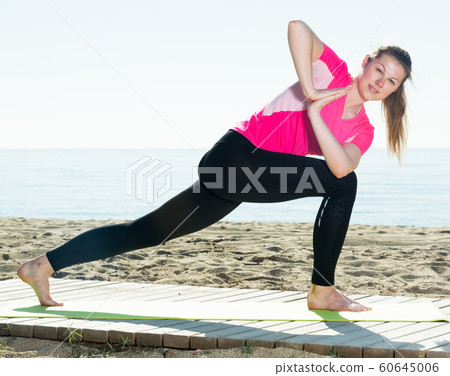 Woman exercising yoga poses on beach Woman exercising yoga poses on beach 60645006