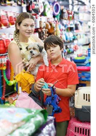 Adult woman with preteen son buying dog clothes Adult woman with preteen son buying dog clothes 60645014