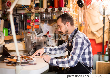 male worker sewing stitches on belt in leather workshop male worker sewing stitches on belt in leather workshop 60645108