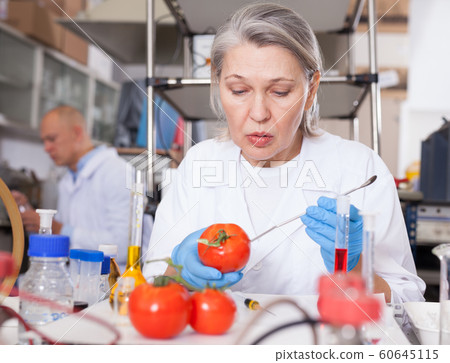 Female geneticist conducting experiments with fruits and vegetables 60645115