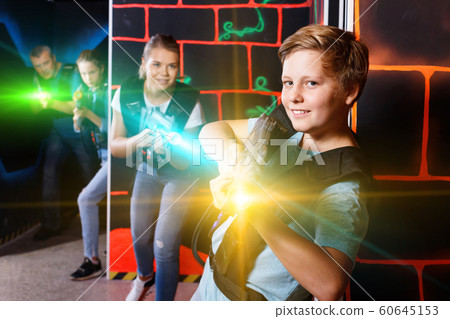 Excited boy aiming laser gun at other players during laser tag g 60645153