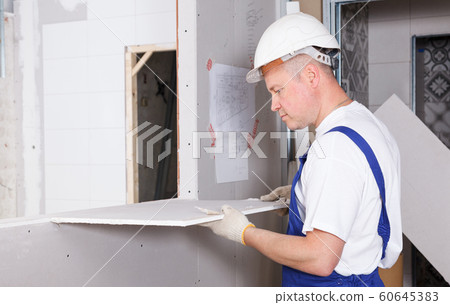 Worker engaged in drywall mounting 60645383