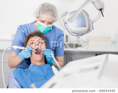 Young man on dental checkup in modern dentist office Young man on dental checkup in modern dentist office 60645449
