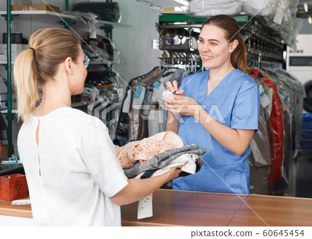 Woman receiving clothing for dry cleaning Woman receiving clothing for dry cleaning 60645454