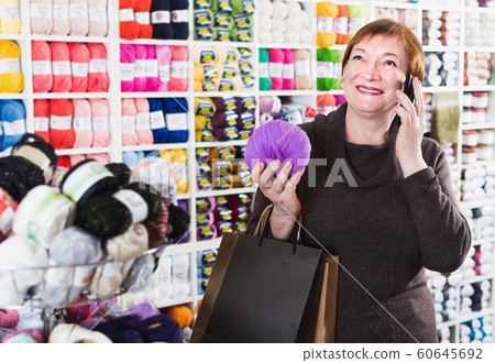 Smiling senior female with smartphone in store Smiling senior female with smartphone in store 60645692