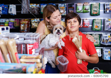 Cheerful woman with preteen son buying dog treats and chews in store to reward their precious pup Cheerful woman with preteen son buying dog treats and chews in store to reward their precious pup 60645700