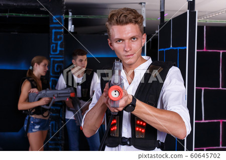 Happy young man with laser pistol and playing laser tag with his friends Happy young man with laser pistol and playing laser tag with his friends 60645702