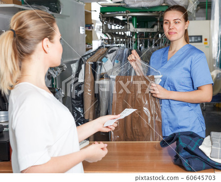 Laundry worker giving clean clothes to client Laundry worker giving clean clothes to client 60645703