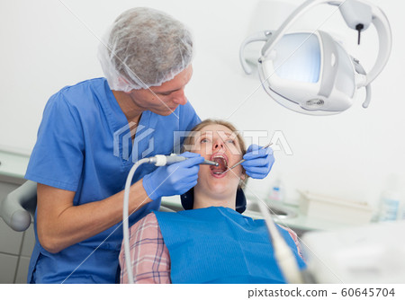Male dentist treating young female patient in dental office Male dentist treating young female patient in dental office 60645704